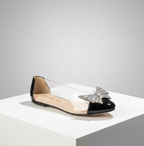 Zapatos planos tipo bailarina con laterales transparentes y un lazo decorativo de cristales en la punta.