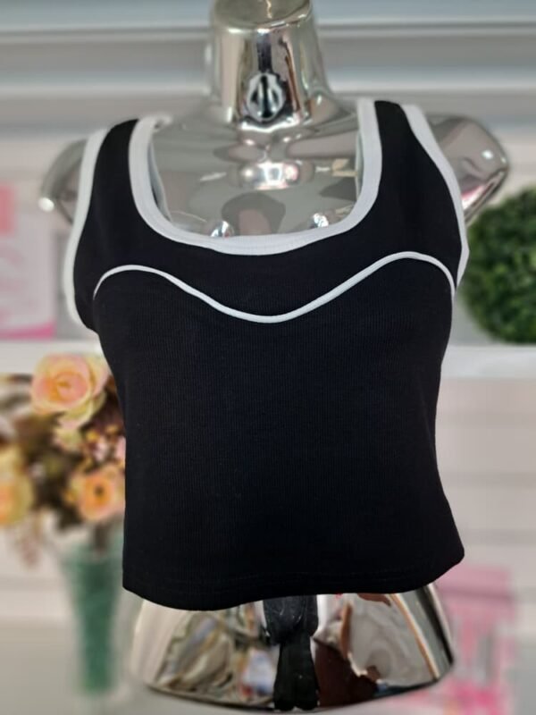 Top corto negro con bordes blancos, diseñado con un estilo deportivo y elástico