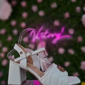 Sandalia de tacón bloque para mujer con diseño acolchado con un detalle metálico circular en la parte frontal y una correa ajustable al tobillo.