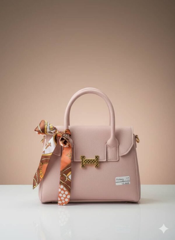 Bolso rosa tipo satchel con diseño estructurado, detalles dorados y un pañuelo decorativo incluido..