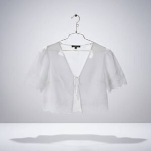 Blusa corta tipo cropped, confeccionada en algodón con bordado inglés, escote en V y frente abierto con lazadas