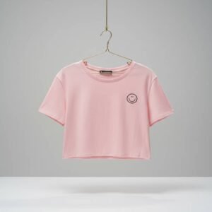 Camiseta corta de color rosa con un pequeño diseño de carita feliz bordado en el pecho.