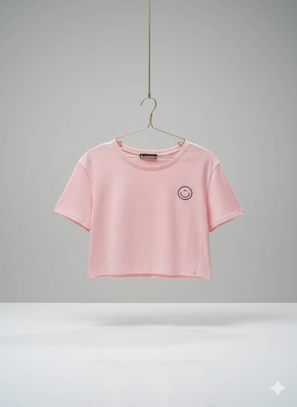 Camiseta corta de color rosa con un pequeño diseño de carita feliz bordado en el pecho.