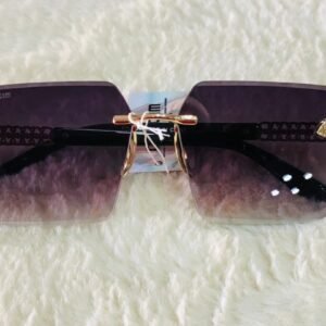 Gafas de sol con diseño cuadrado sin montura, detalles metálicos dorados en las patillas y lentes con degradado.