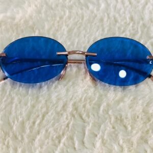 Gafas de sol de estilo "Morpheus" con lentes ovaladas azules sin montura y una estructura metálica dorada.