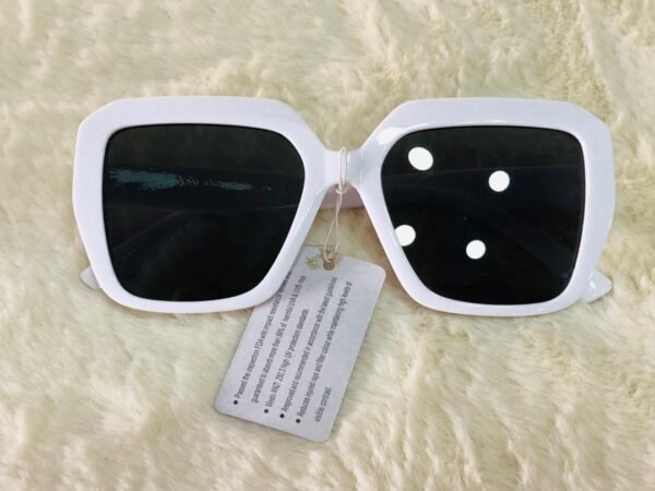 Gafas de sol de marco cuadrado blanco con lentes oscuros que ofrecen protección contra los rayos UVA y UVB.