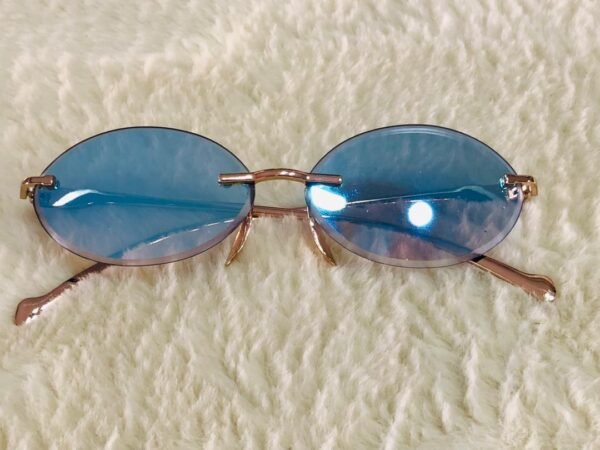 Gafas de sol de estilo vintage ovaladas sin montura con lentes azules y marco dorado