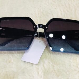 Gafas de sol marca COCOIM con diseño oversize cuadrado con lentes degradados y detalles de remaches.