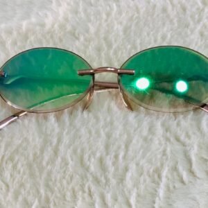 Gafas de sol con diseño redondo y sin montura, con lentes espejadas de color verde y montura dorada.