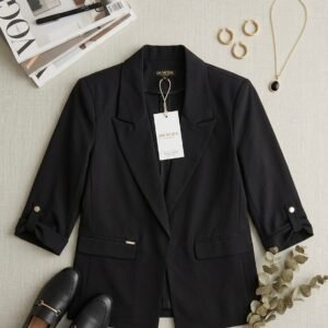 Blazer negro con diseño estructurado con solapas de pico, mangas tres cuartos con detalles de botones dorados y bolsillos con solapa.