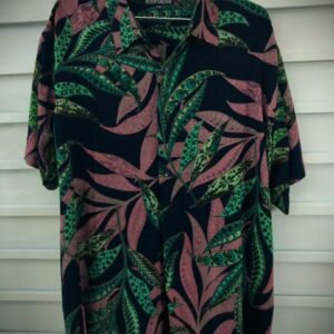 Camisa hawaiana con estampado de hojas tropicales en tonos oscuros, verdes y rosados, estilo ideal para un look casual o veraniego.