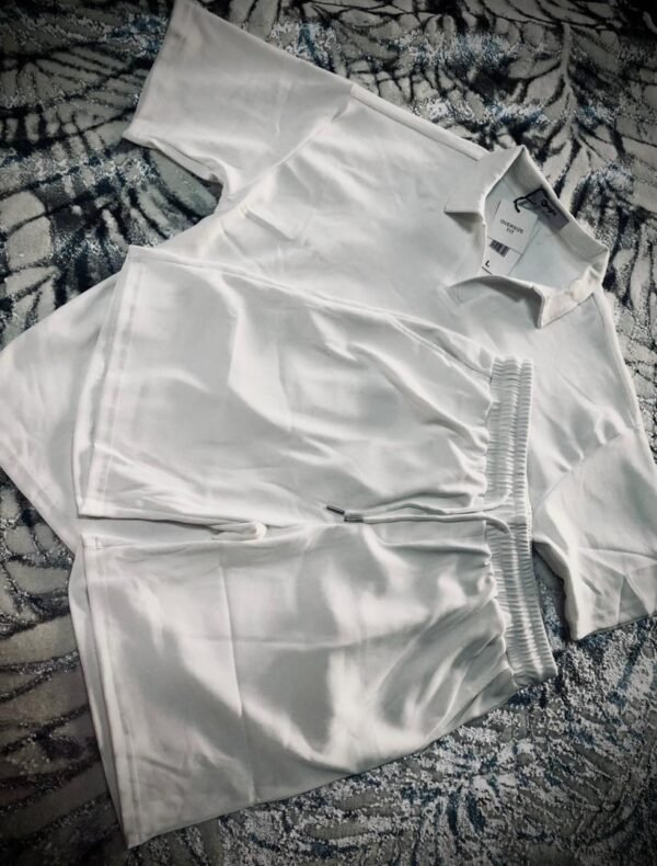 Conjunto de ropa para hombre compuesto por una camisa tipo polo y un short de color blanco.
