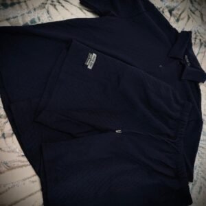 Conjunto de ropa deportiva de color negro compuesto por una camiseta tipo polo y unos pantalones cortos