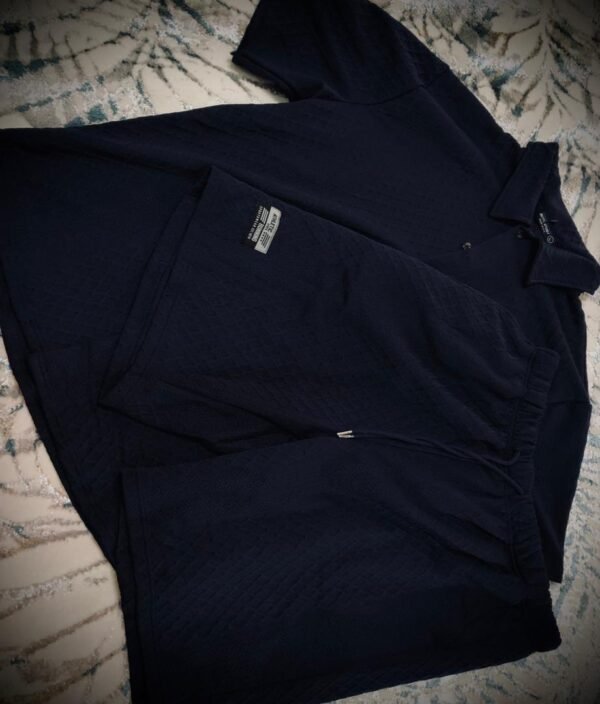 Conjunto de ropa deportiva de color negro compuesto por una camiseta tipo polo y unos pantalones cortos