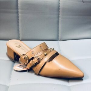 Zapatillas tipo mule de tacón bajo y punta afilada, caracterizado por detalles de hebillas y tachuelas