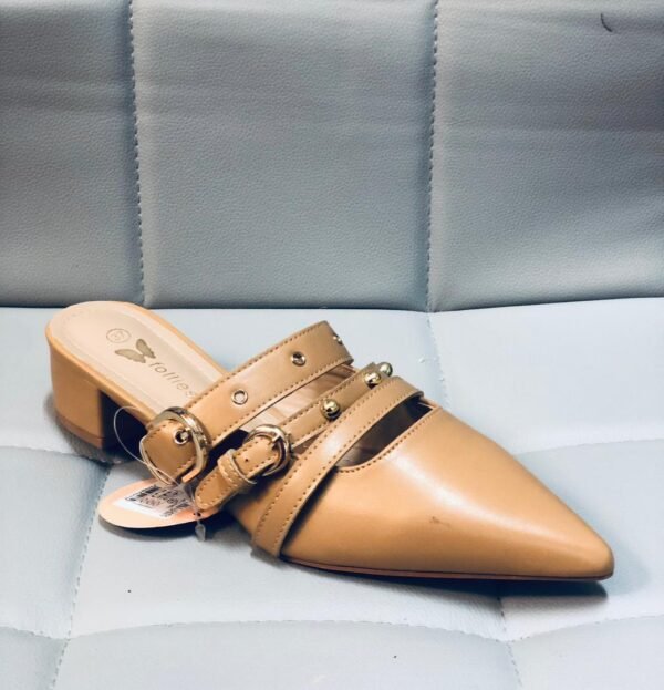 Zapatillas tipo mule de tacón bajo y punta afilada, caracterizado por detalles de hebillas y tachuelas