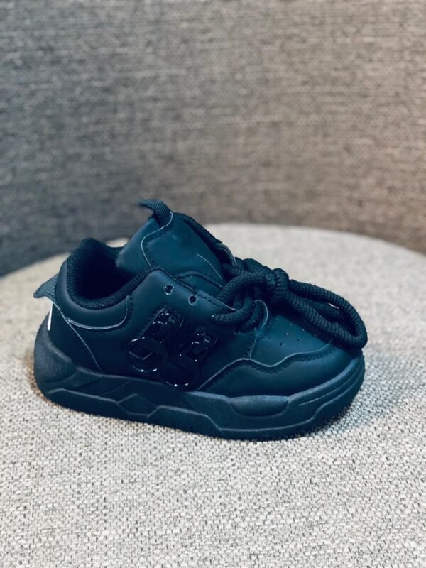 Zapatillas deportivas infantiles de color negro con un diseño grueso y plataforma.