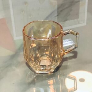 Taza de vidrio color ámbar con un diseño facetado en la base.
