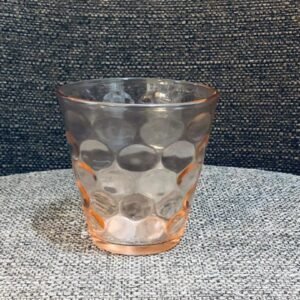 Vaso de vidrio de colección con un patrón de círculos concéntricos en su interior, diseñado para crear patrones geométricos de luz y sombra cuando está lleno.
