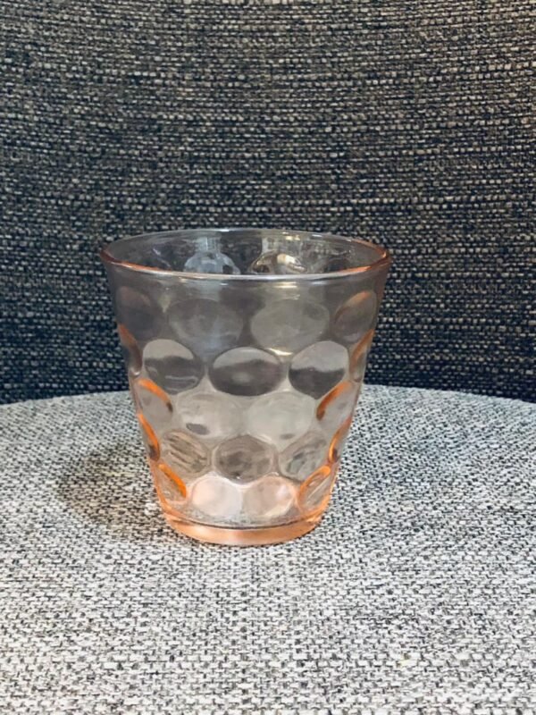 Vaso de vidrio de colección con un patrón de círculos concéntricos en su interior, diseñado para crear patrones geométricos de luz y sombra cuando está lleno.