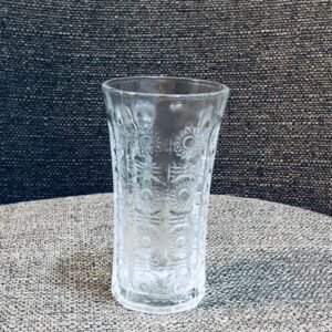 Vaso de vidrio o cristal con un patrón decorativo de círculos o motivos geométricos tallados.