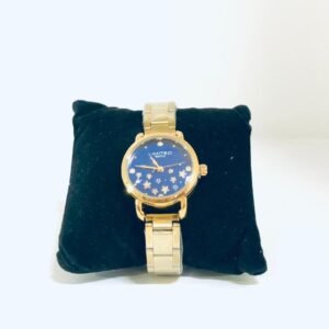 Reloj de la marca Coach con un diseño de carátula azul con motivos florales y una correa dorada