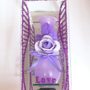 Arreglo de decoración para el hogar que consiste en un florero púrpura con una rosa artificial