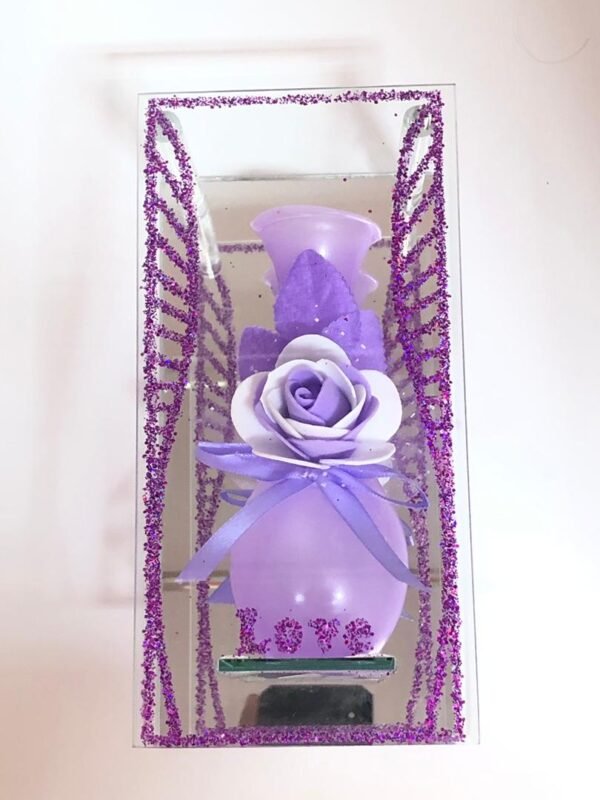 Arreglo de decoración para el hogar que consiste en un florero púrpura con una rosa artificial
