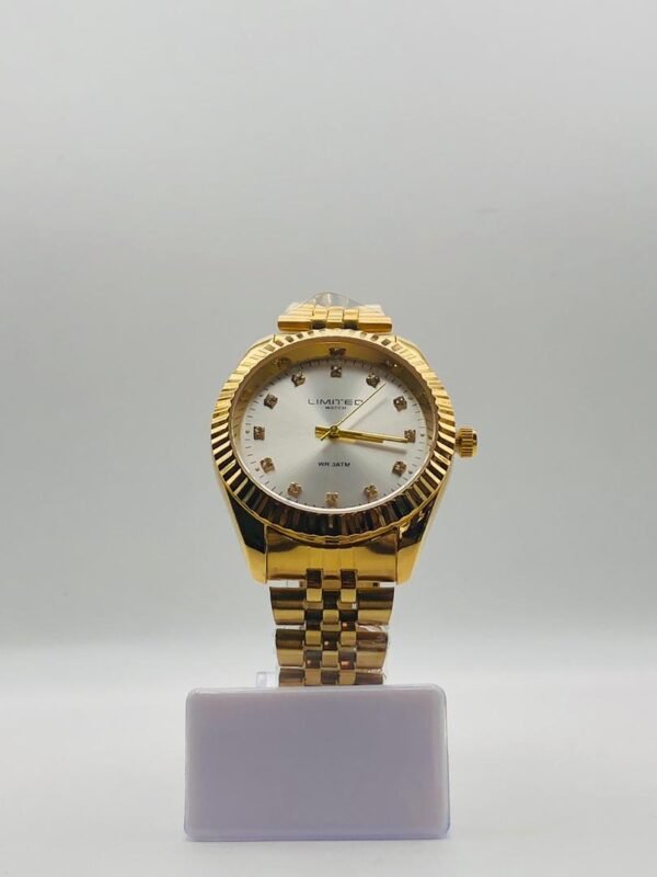 Reloj analógico de cuarzo en tono dorado con una esfera blanca y marcadores de hora con incrustaciones de cristal